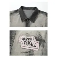 Джинсова куртка «RES TARALL»: сіра куртка з чорними рукавами, прикрашена яскравими принтами та нашивками, виготовлена з 100% бавовни.